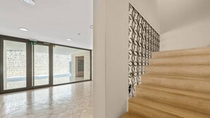 A modern interior with a wooden staircase, a patterned wall, and a glass door leading to an outdoor area.