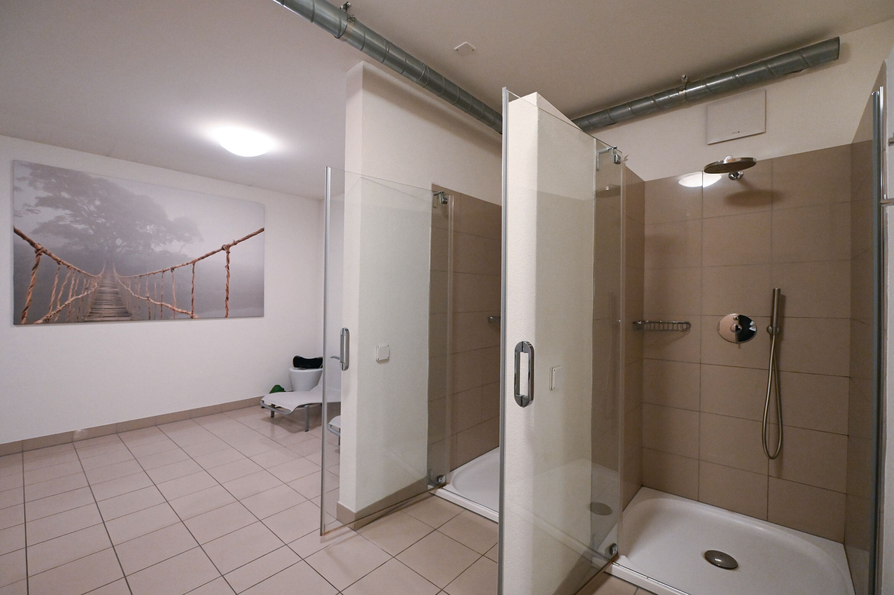 A modern bathroom with a glass-enclosed shower, a toilet, and a bench.