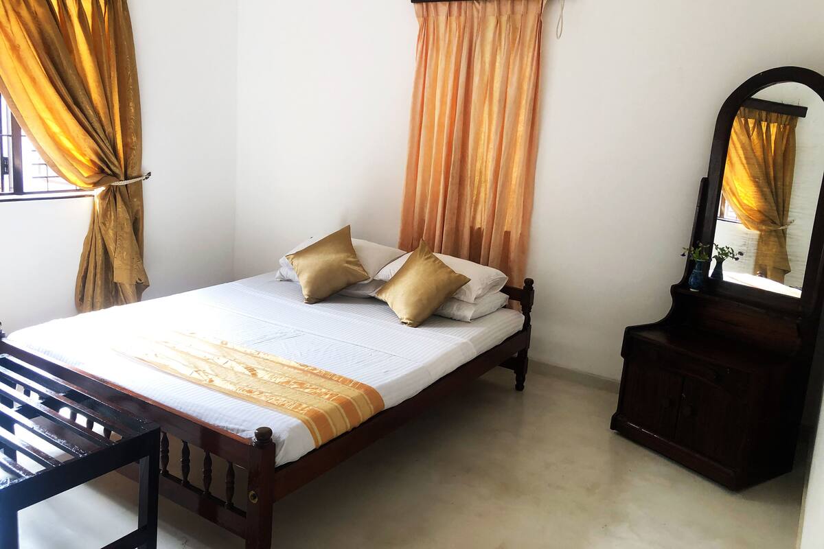A neatly made bed with a wooden frame, two pillows, and a striped bedspread.