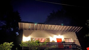 Ein Haus mit einer Steinauffahrt, einer Holzveranda und einer roten Tür.