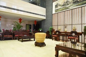 Experience the elegant lobby with traditional furniture, potted plants, and a decorative wall.