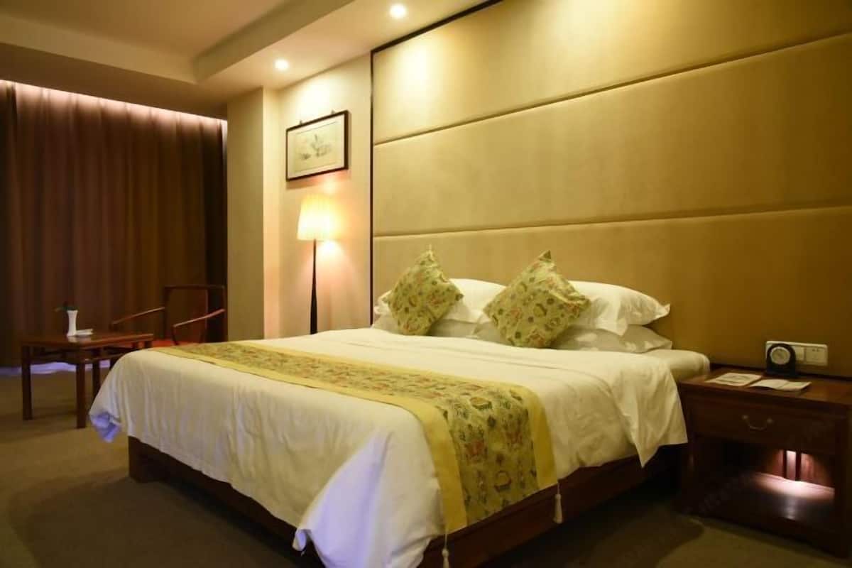 A hotel room with a large bed, a bedside table, a lamp, and a radio.