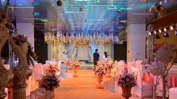 A wedding venue with a central aisle, floral arrangements, and a chandelier. - Spring Hotel (Dacheng)
