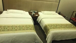 A hotel room with two single beds, a nightstand with a lamp, a telephone, and a small table with a chair. - Spring Hotel (Dacheng)
