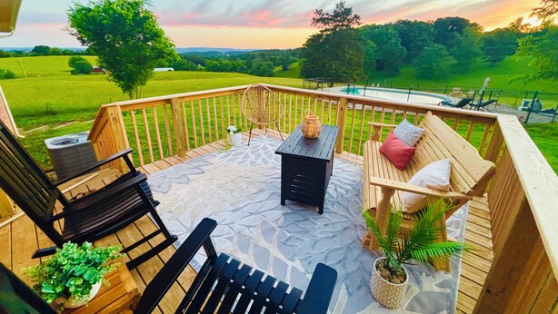A wooden deck with outdoor furniture, a hot tub, and a view of a green landscape. - Luxury Home w/private Pool, Mt Views, 85” Roku Movie Room, Arcade, & King Bed! (Talbott)