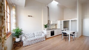 Een compacte woonruimte met een kitchenette, een eethoek en een bank.