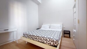 Een slaapkamer met een bed, een bureau en een kledingkast.