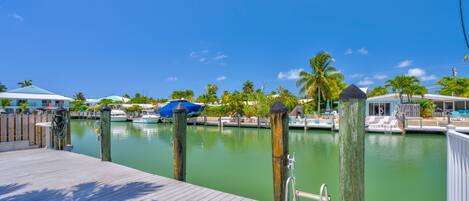 A wooden dock with a metal ladder, a clear view of the marina, and several boats docked.