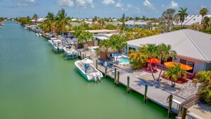 A marina with boats docked, a pool area, and a building with outdoor seating. - Cabana Club, Kayaks, Pets, Boat Dock, Near Golf! (Key Colony Beach)
