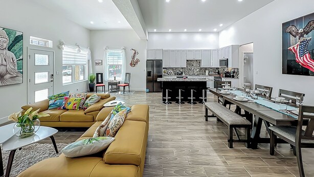 A modern living room with a sofa, dining table, and kitchen area.