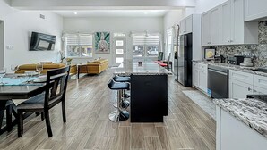 A spacious living area with a dining table, sofa, and a kitchen with modern appliances.