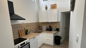 Eine kleine Küche mit weißen Schränken, einer schwarzen Dunstabzugshaube und einer Holz Arbeitsplatte.