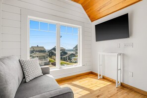 Une pièce avec une grande fenêtre, un radiateur blanc et un canapé gris.