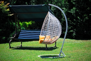 A garden chair with a mesh backrest and a cushion, positioned on a grassy lawn.