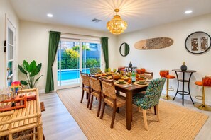A dining area with a table set for four, surrounded by chairs, a large window with curtains, and a view of a swimming pool. - A tropical Scottsdale escape made for friends and family to gather, relax and reconnect. Enjoy your private pool, tiki bar and inviting spaces to spend time together—all just a 10-minute drive from Old Town (Scottsdale)