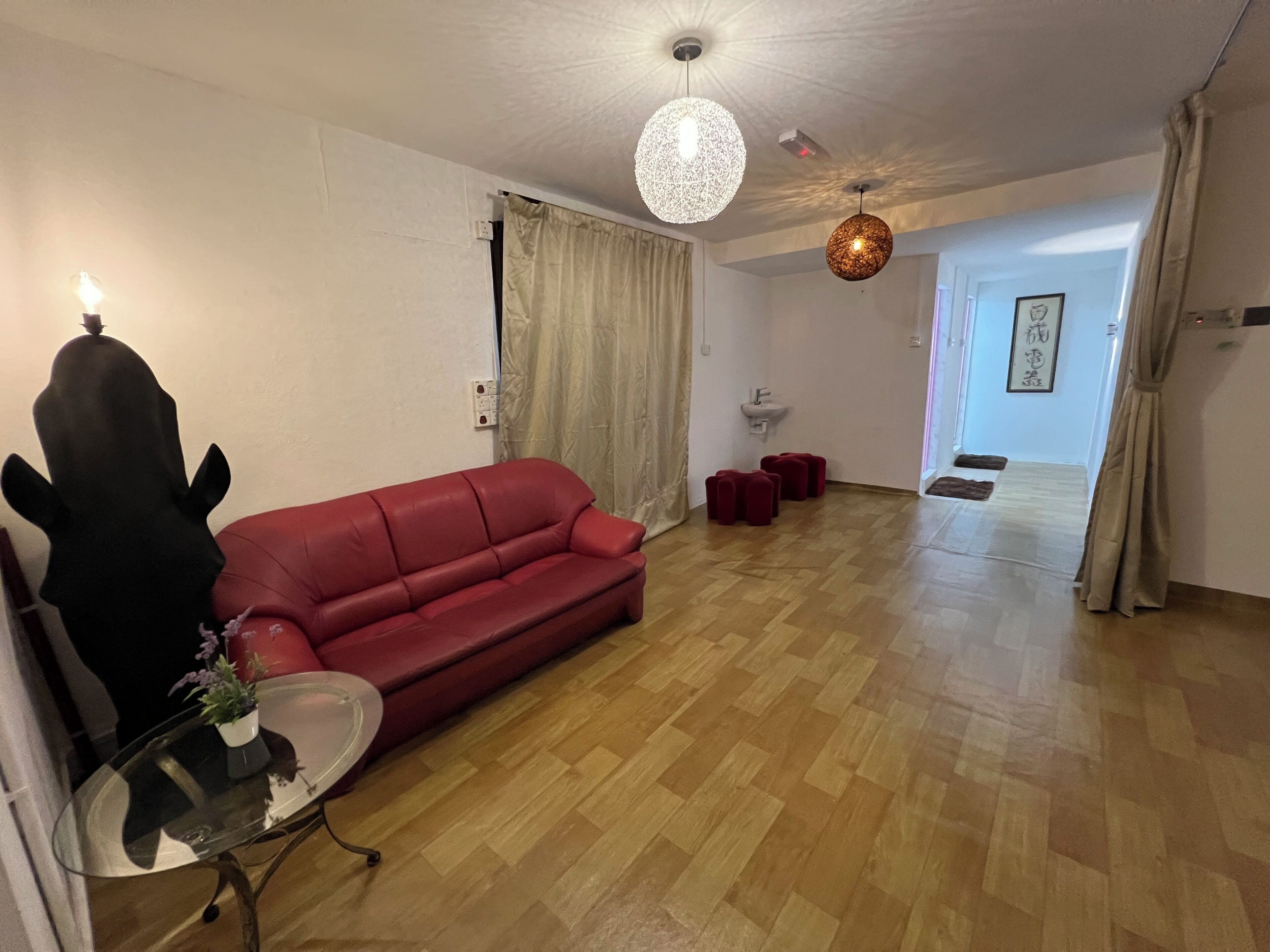 A living room with a red sofa, a glass coffee table, and a hanging light fixture.