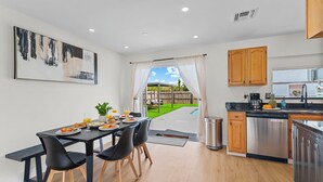 Una cocina moderna con comedor, un cuadro grande y vistas a un patio con piscina.