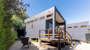 A modern house with a deck, a chair, and a gravel path. - RitoKazo (Quintero)