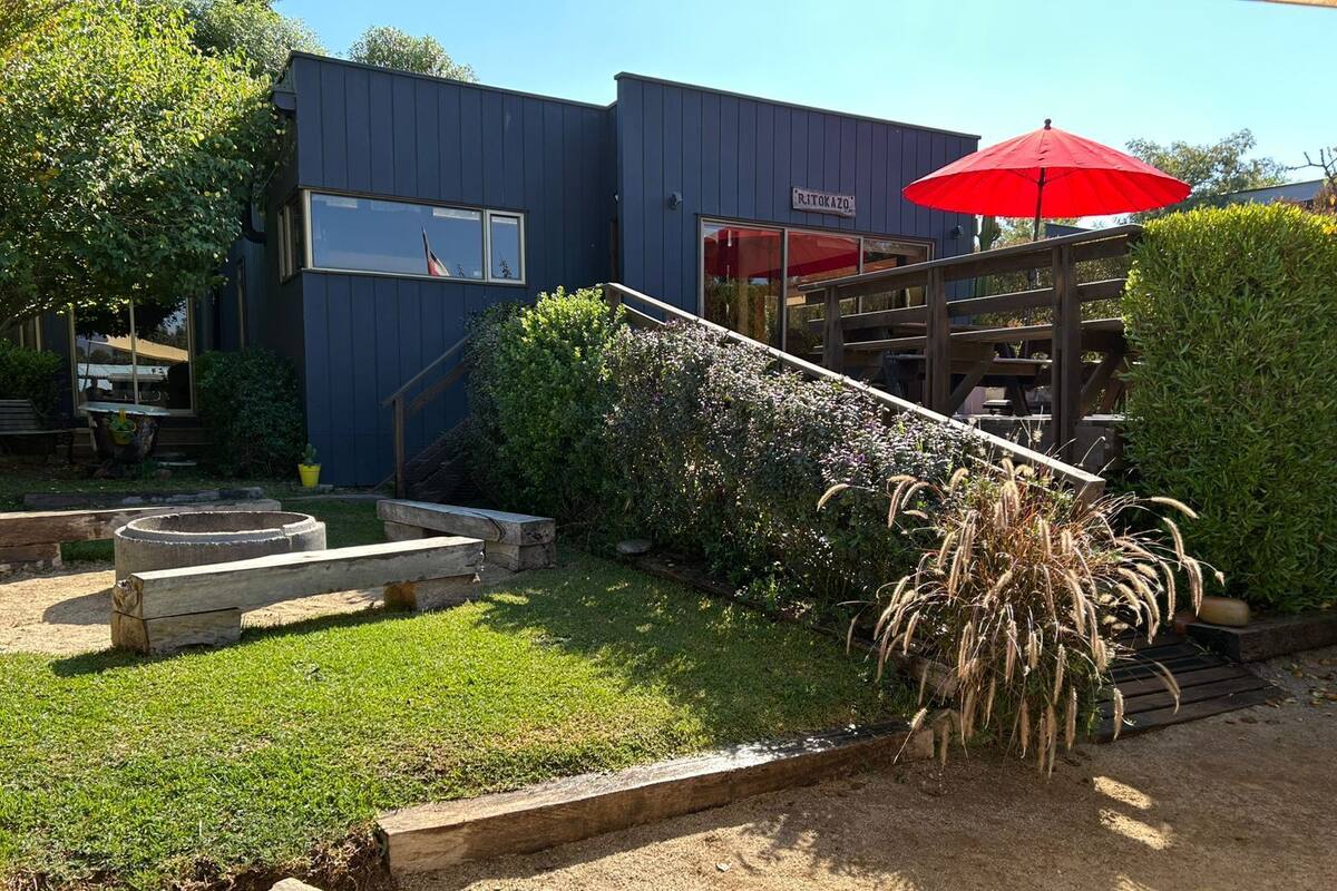 A modern building with a dark exterior, a wooden deck, and a red umbrella.