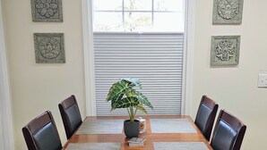 A dining table with four chairs, a potted plant, and decorative wall art. - Scenic Serene Spacious Studio 65in Smart TV WiFi Sun Ticket Laundry Full Kitchen (Decatur)