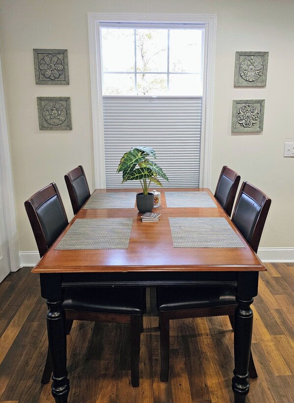 A dining table with four chairs, a potted plant, and decorative wall art. - Scenic Serene Spacious Studio 65in Smart TV WiFi Sun Ticket Laundry Full Kitchen (Decatur)