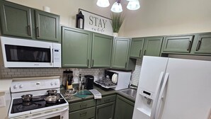 A kitchen with green cabinets, white appliances, and a 'STAY awhile' sign. - Scenic Serene Spacious Studio 65in Smart TV WiFi Sun Ticket Laundry Full Kitchen (Decatur)