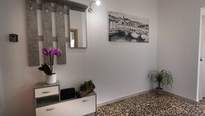 A modern bathroom with a marble vanity, a large mirror, a black and white cityscape painting, and a patterned floor. - Florence Oasis (Firenze)