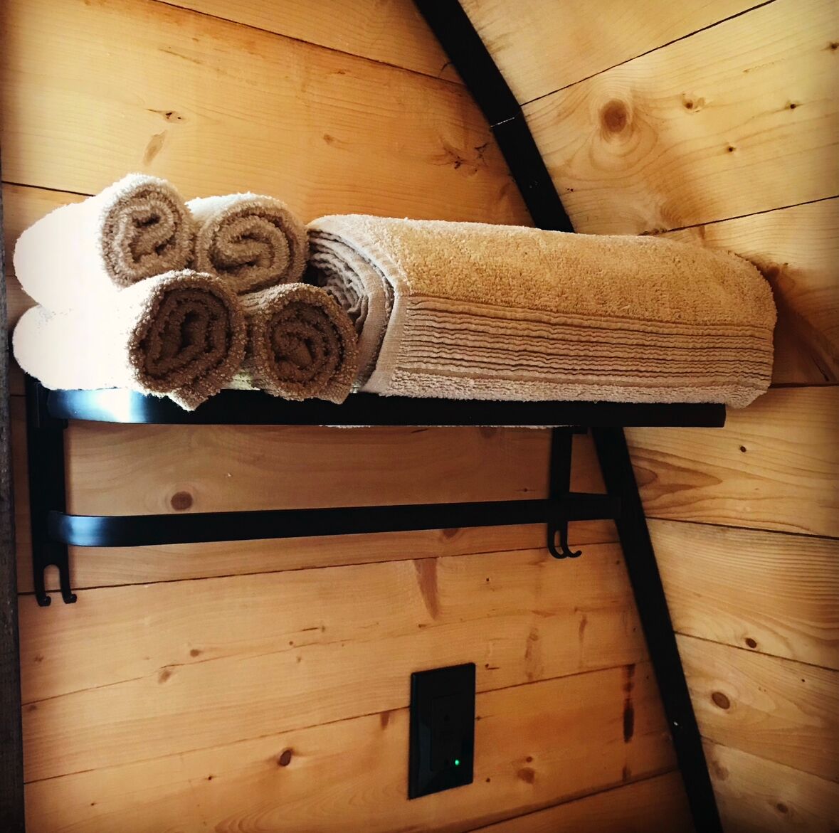 Techo de madera con un perchero que sostiene toallas enrolladas.