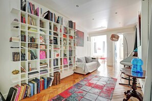 Een ruime kamer met een grote boekenkast vol boeken, een comfortabele bank en een houten vloer.