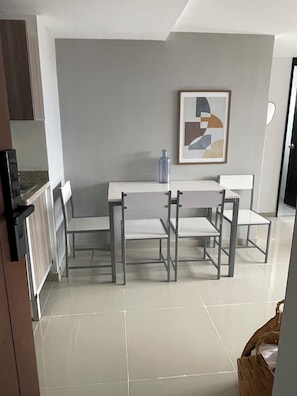 Ein Essbereich mit Tisch und Stühlen, ein gerahmtes abstraktes Gemälde an der Wand und eine durchgehende offene Tür zur Küche.