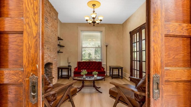 Une pièce avec une cheminée, un canapé en velours rouge, une table basse en bois et des fauteuils en cuir.
