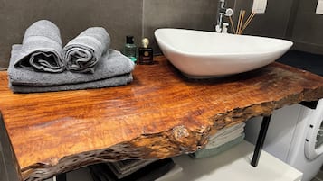 Une salle de bain avec un meuble-lavabo en bois, un lavabo blanc et des serviettes.