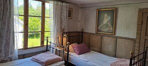A room with a bed, a bedside table, a lamp, and a window with curtains.