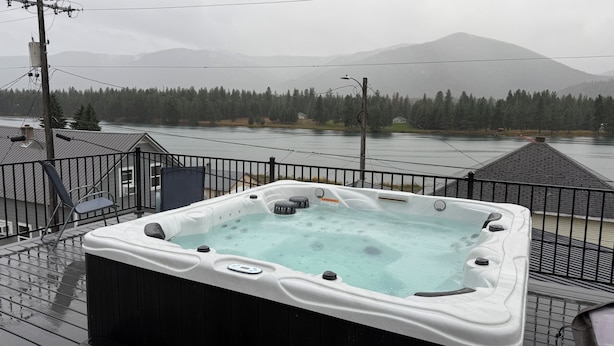 Un jacuzzi en una terraza con vista a un lago y montañas.