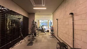 A gym with exercise equipment, a wall-mounted rack, and a bench.