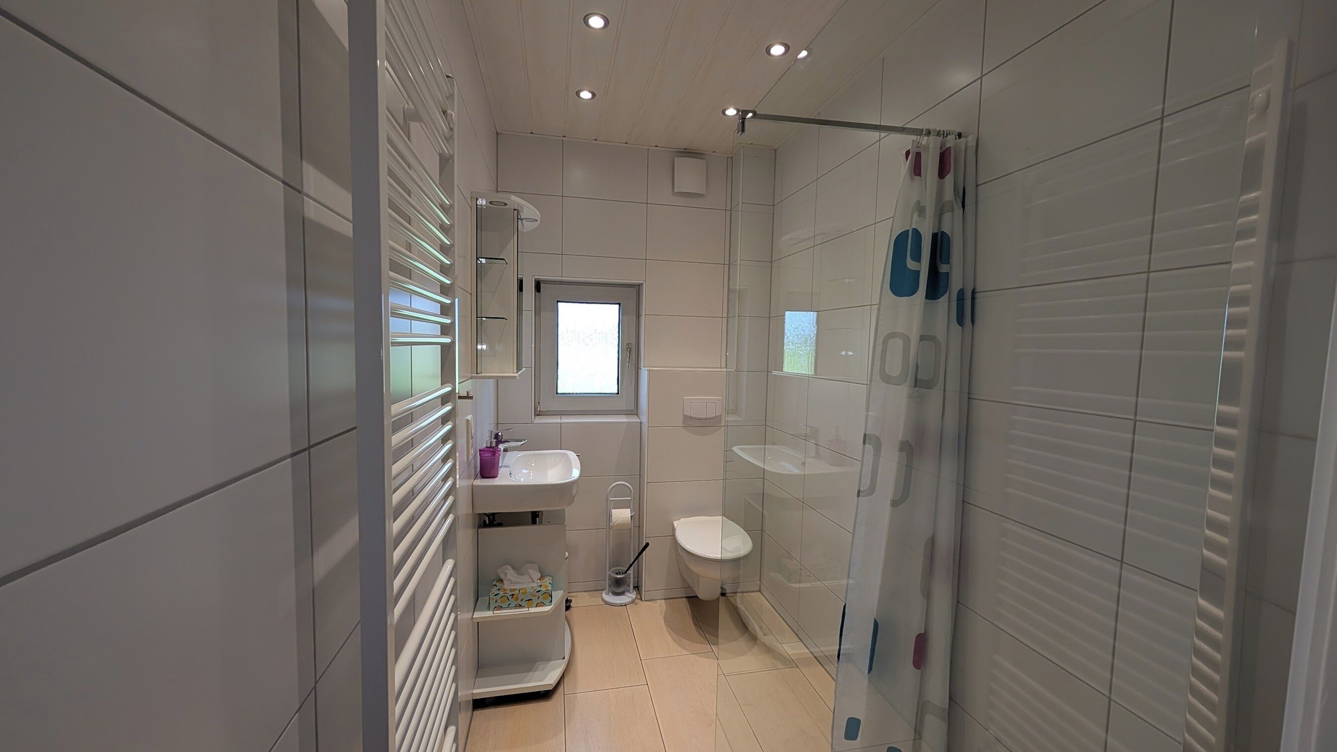 Een moderne badkamer met toilet, wastafel en douche.