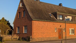 A red brick building with a steeply pitched roof, a wooden door, and a small window.