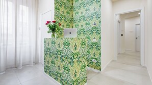 A reception area with a patterned wall, a laptop, and a vase with flowers. - Recently renovated, within walking distance of the Vatican and 180mt from the metro. (Roma)