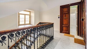 A staircase with ornate black metal railings and wooden handrails, leading to a wooden door with a glass panel. - Recently renovated, within walking distance of the Vatican and 180mt from the metro. (Roma)