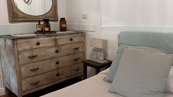 Une chambre à coucher comprenant un lit, une commode, un miroir et un anneau lumineux fixé au mur.