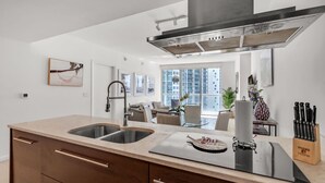 A modern kitchen with a central island, double sinks, and a stainless steel range hood. - Icon Brickell Retreat | 1BR + Spa, Pool, Views (Miami)