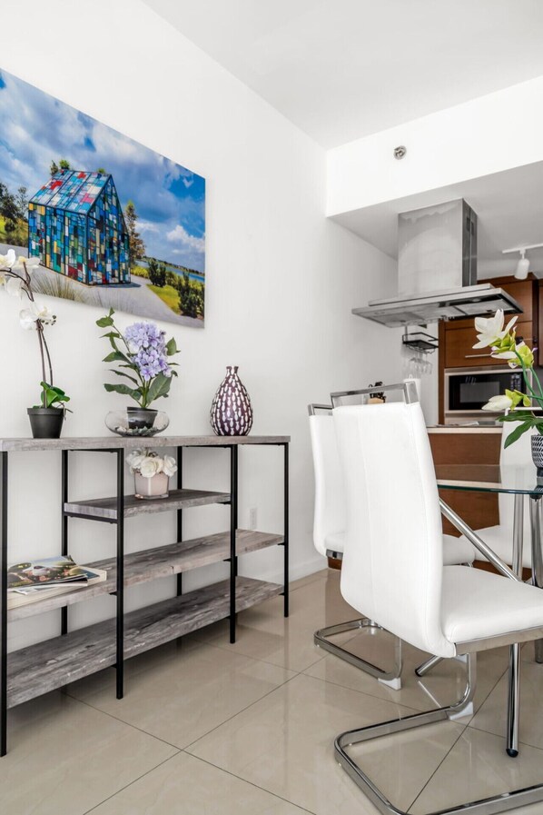 A modern kitchen with white cabinets, a stainless steel range hood, and a microwave.
