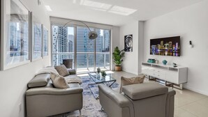 A modern living room with a sofa set, a coffee table, and a TV mounted on the wall. - Icon Brickell Retreat | 1BR + Spa, Pool, Views (Miami)