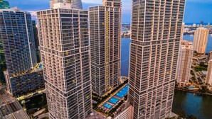 A high-rise building with a modern architectural design, featuring a prominent vertical structure and a rooftop pool. - Icon Brickell Retreat | 1BR + Spa, Pool, Views (Miami)