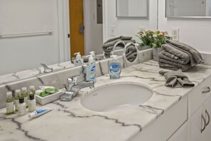 Casa de banho com lavatório de mármore, amenities e toalhas.