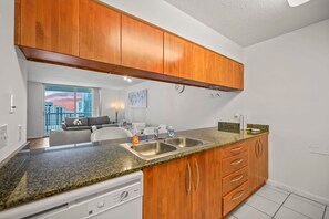 A modern kitchen with wooden cabinets, a granite countertop, and a built-in dishwasher.