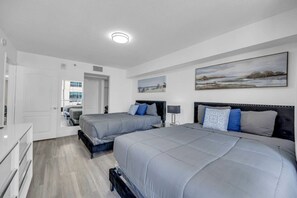 Un dormitorio moderno con dos camas, un tocador blanco y un cuadro en la pared.