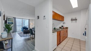 A modern apartment with a dining area, kitchen, and a balcony with a city view.