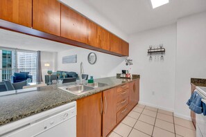 A modern kitchen with granite countertops, wooden cabinets, a built-in dishwasher, and a coffee station.