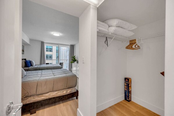 Habitación de hotel con cama, armario y ventana con vistas a la ciudad.